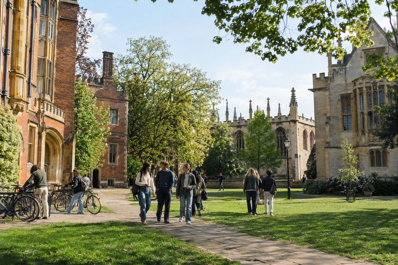 Students walking across a lawn between red brick university buildings in England
